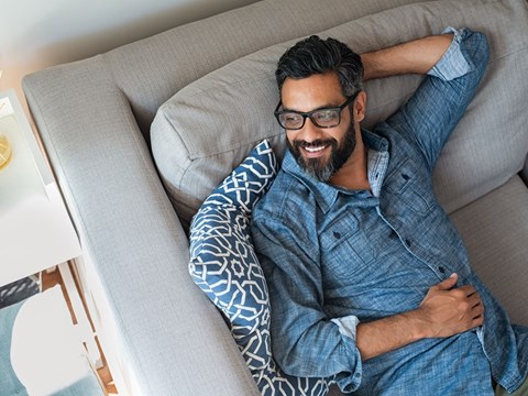 a man laying on a couch with his head on a pillow